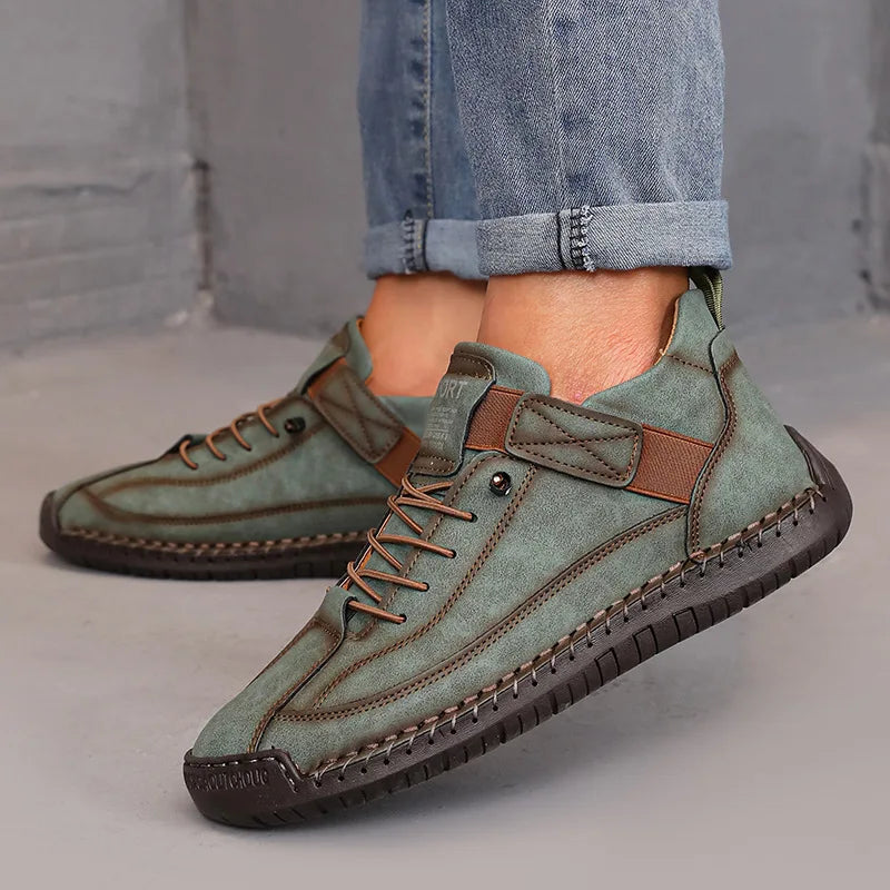 Green leather shoes with brown accents worn with rolled-up jeans on a neutral background