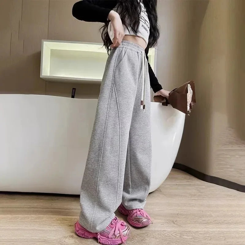 Person wearing gray sweatpants and pink shoes in a room with a white bathtub.