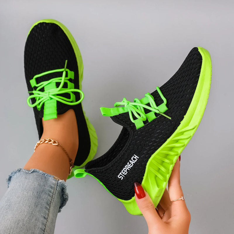 Black and green athletic shoes with 'Stealth' branding held by a person against a gray background