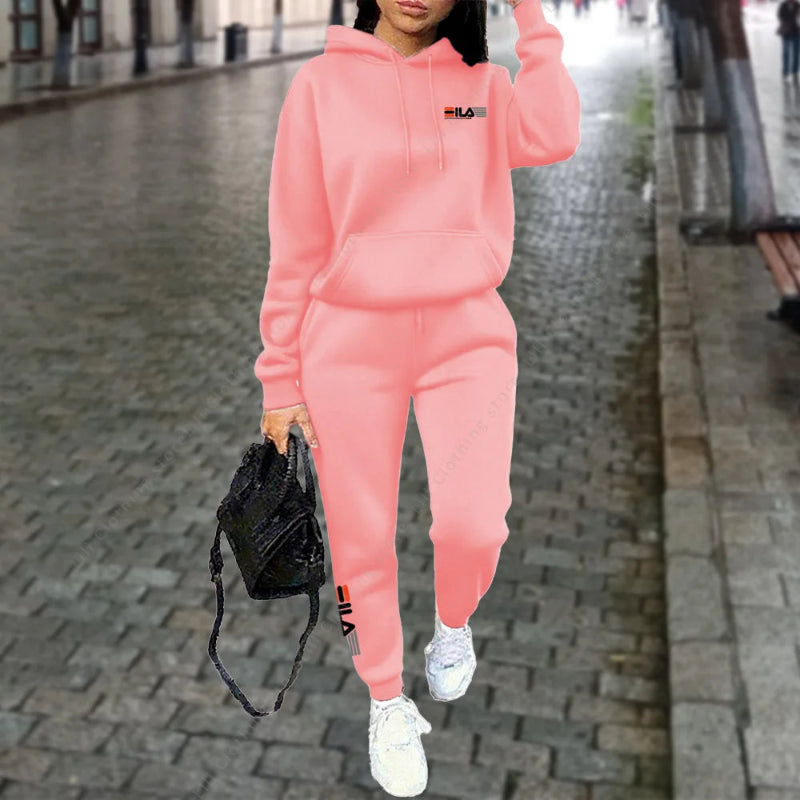 Person wearing a pink tracksuit with visible branding on a blurred street background