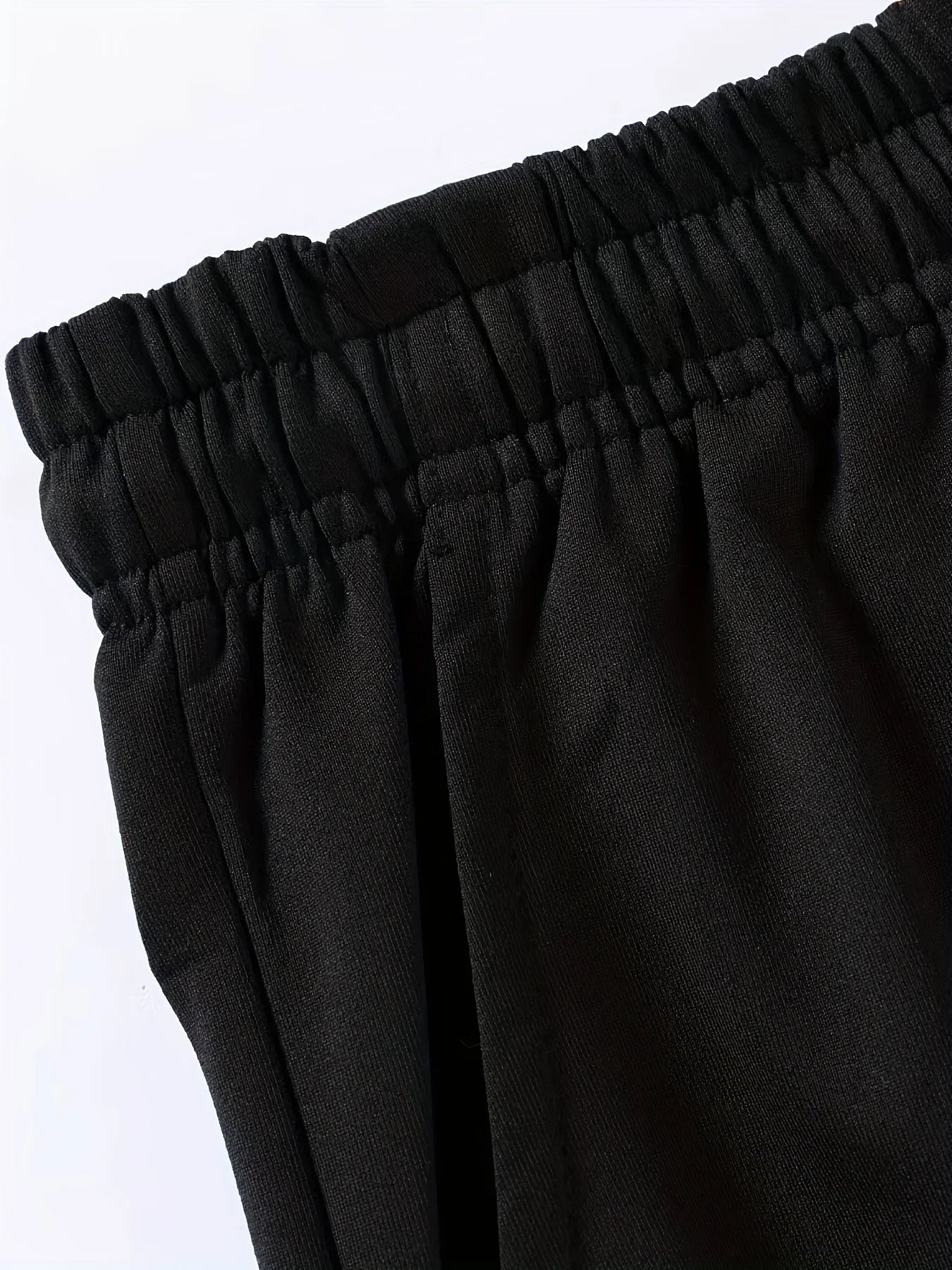 Close-up of black pants with an elastic waistband on a white background