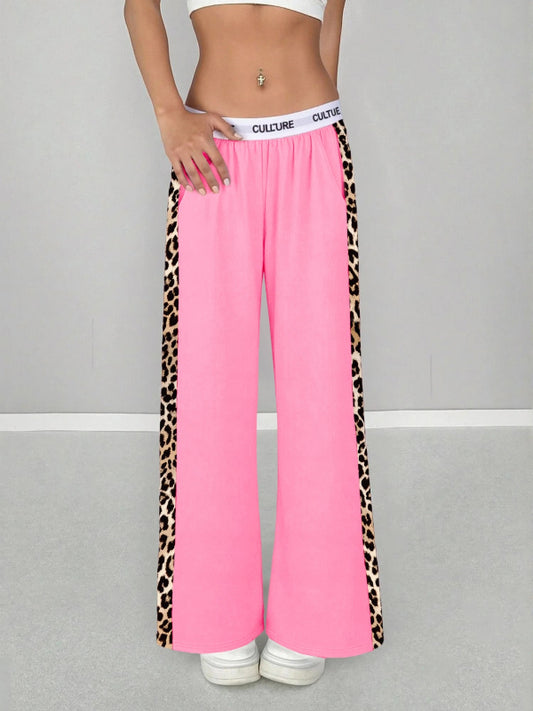 Pink pants with leopard print side panels on a gray background