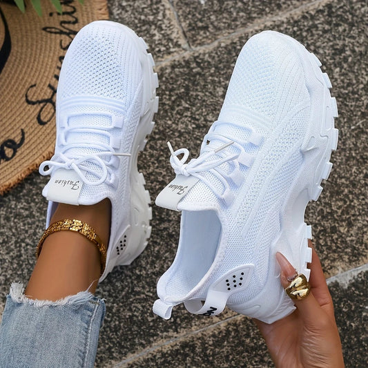 White sneakers held by a person on a textured surface