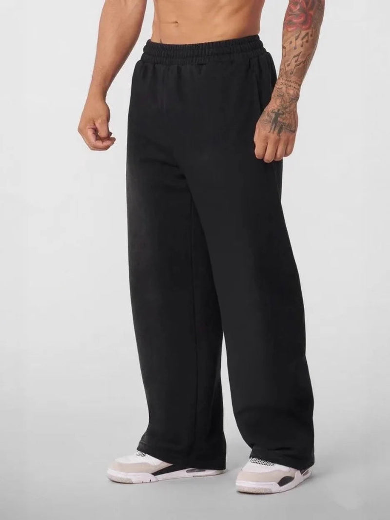 Person wearing black sweatpants on a plain background