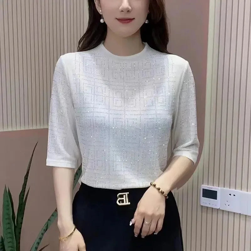 Woman wearing a white textured top and black skirt against a neutral wall.