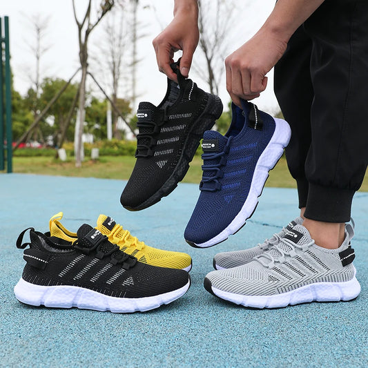 Four pairs of sneakers in black, yellow, blue, and gray held by a person outdoors.