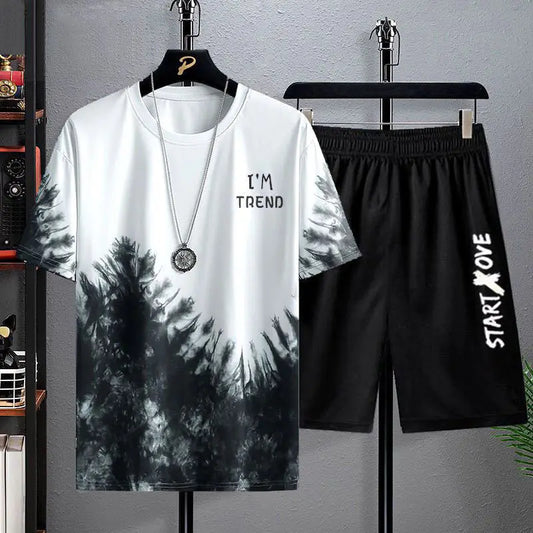 Tie-dye t-shirt and black shorts on hangers against a gray wall.