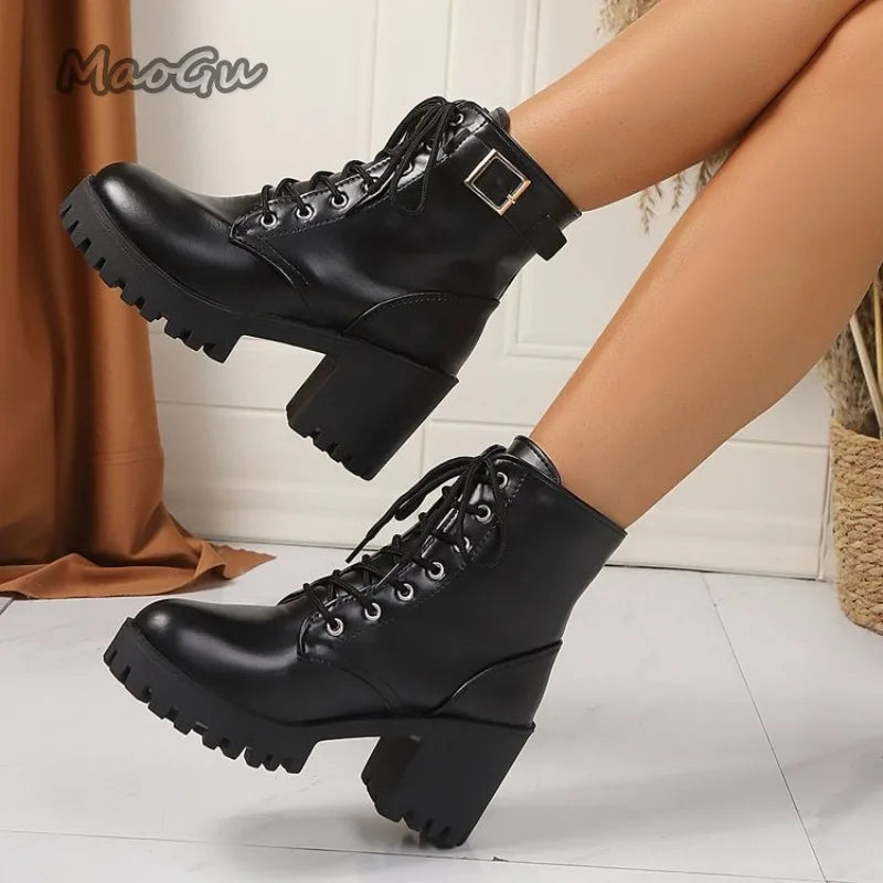 Black lace-up boots worn by a person on a light wooden floor.