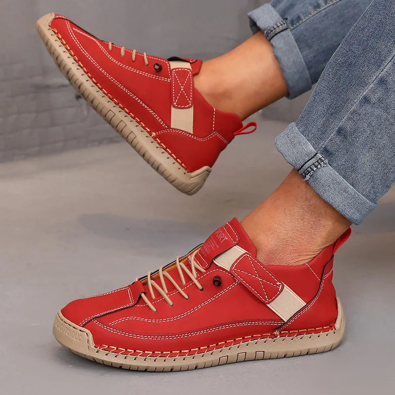 Red sneakers with beige accents worn by a person on a gray floor.