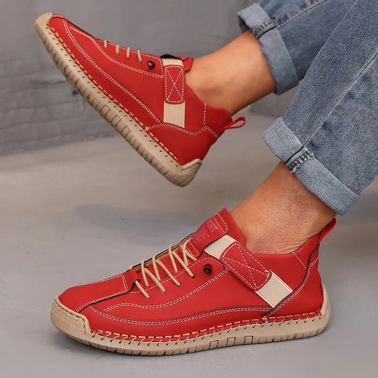 Red sneakers with beige accents worn by a person on a gray floor.