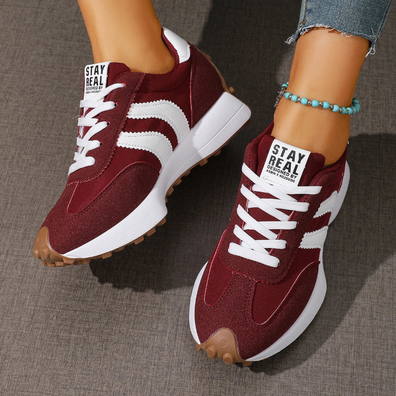 Maroon sneakers with white soles and laces on a neutral background