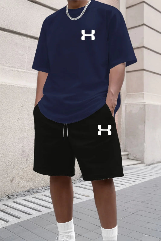 Person wearing navy Under Armour t-shirt and black shorts with brand logo, standing against a stone wall.