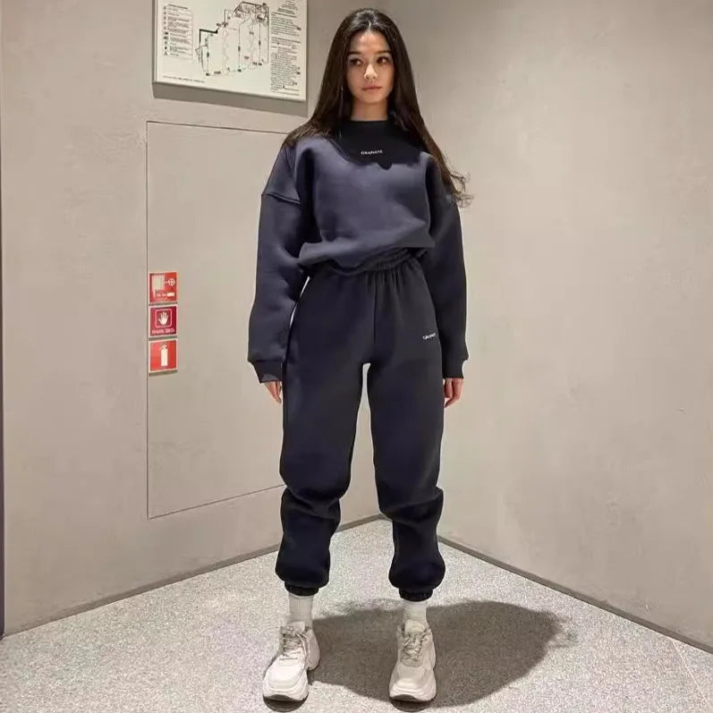 Person wearing a navy blue tracksuit standing in an indoor setting.