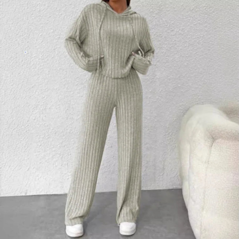 Person wearing a green ribbed knit outfit against a white wall.