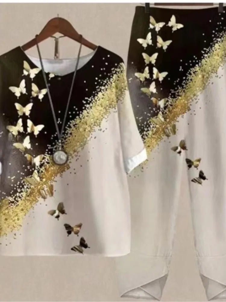 Black and white dress with gold accents and butterfly designs on a hanger.