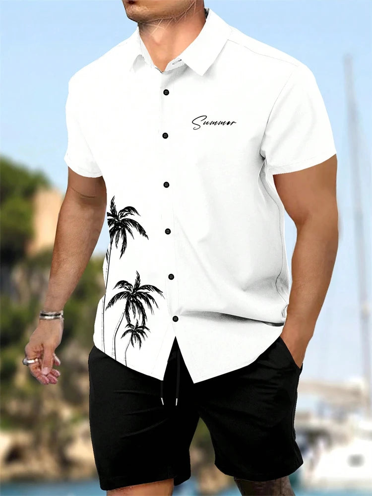 Man wearing a white shirt with palm tree design and black shorts, standing outdoors.