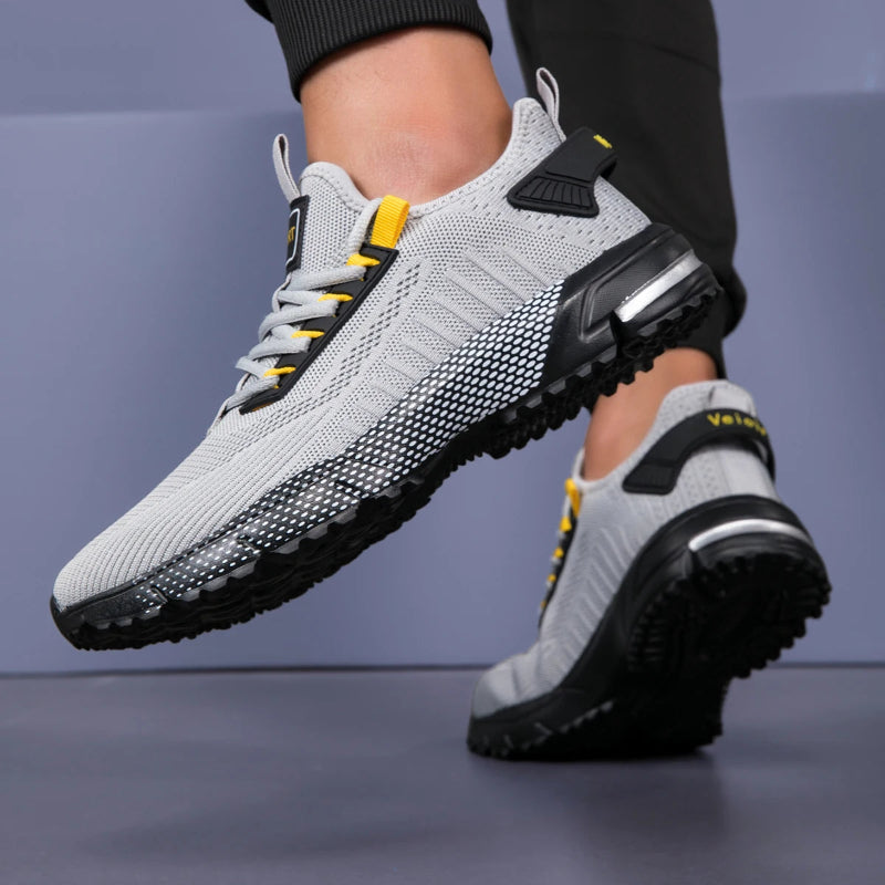 Gray and black athletic shoes with yellow accents on a gray background