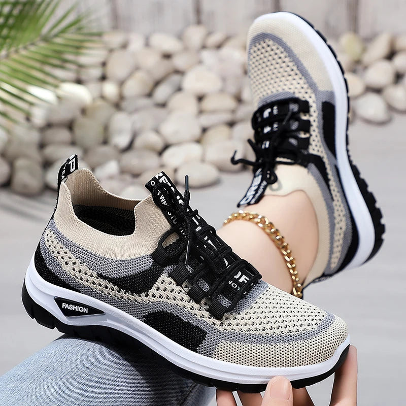 Beige and black sneakers worn by a person sitting on a stone surface.