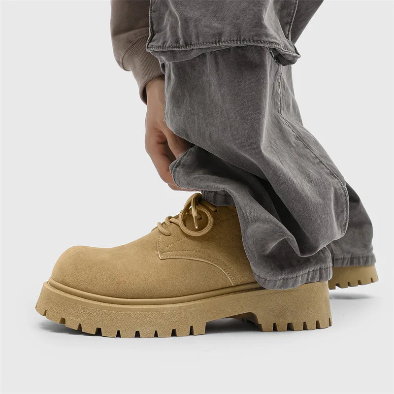 Tan work boots worn with gray pants on a light gray background