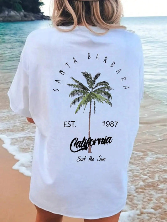 Person wearing a white t-shirt with 'Santa Barbara, California' text and palm tree graphic on a beach.