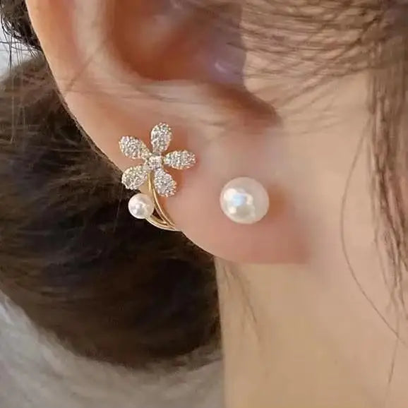Close-up of an ear wearing a floral earring with pearl accents.