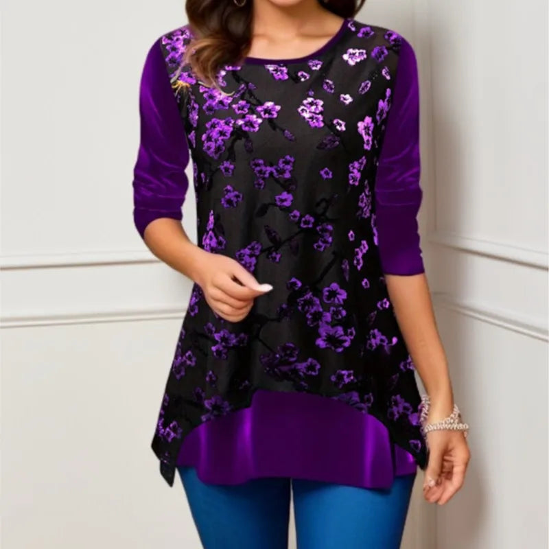 Woman wearing a black floral top with purple accents against a white wall.