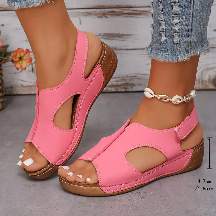 Pink sandals with brown soles worn by a person on a neutral background