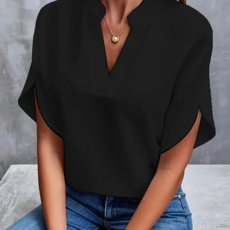 Person wearing a black top and blue jeans against a gray background