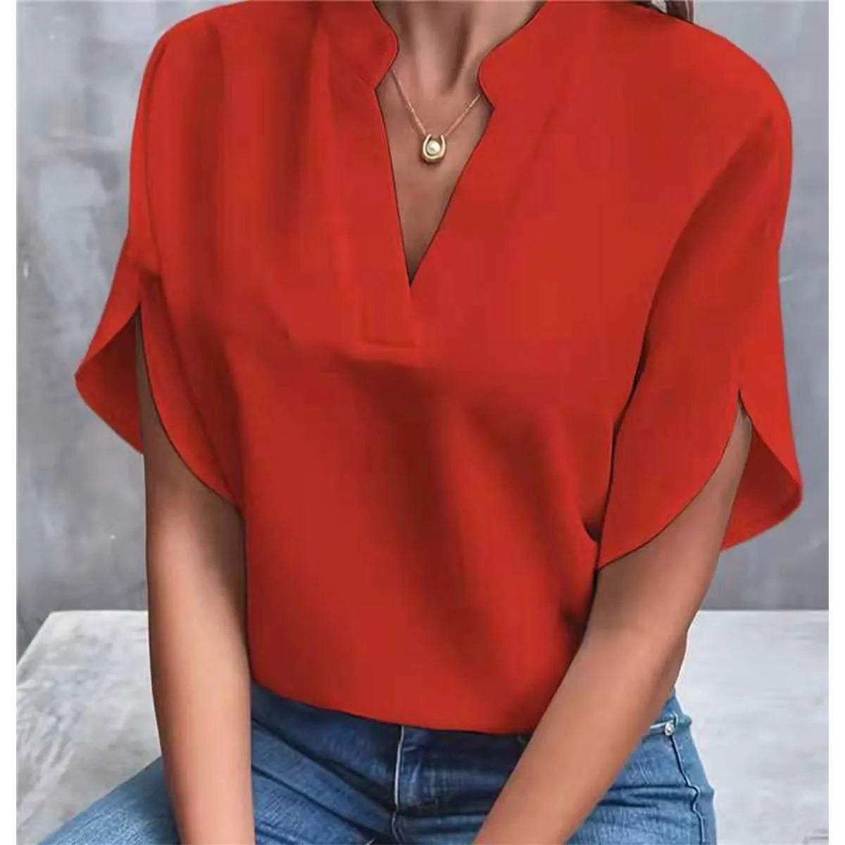 Red blouse with short sleeves worn by a person against a gray background