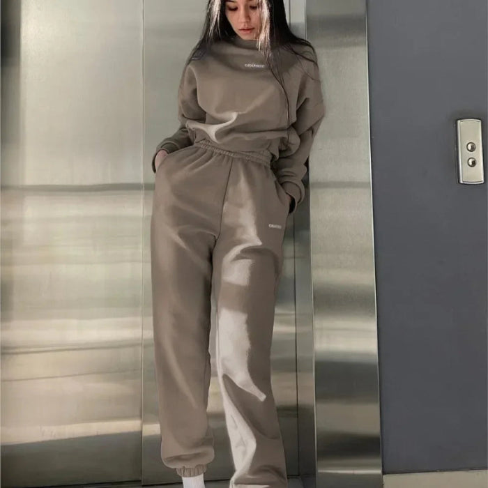 Person wearing a beige tracksuit standing in an elevator.