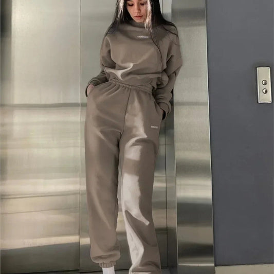 Person wearing a beige tracksuit standing in an elevator.