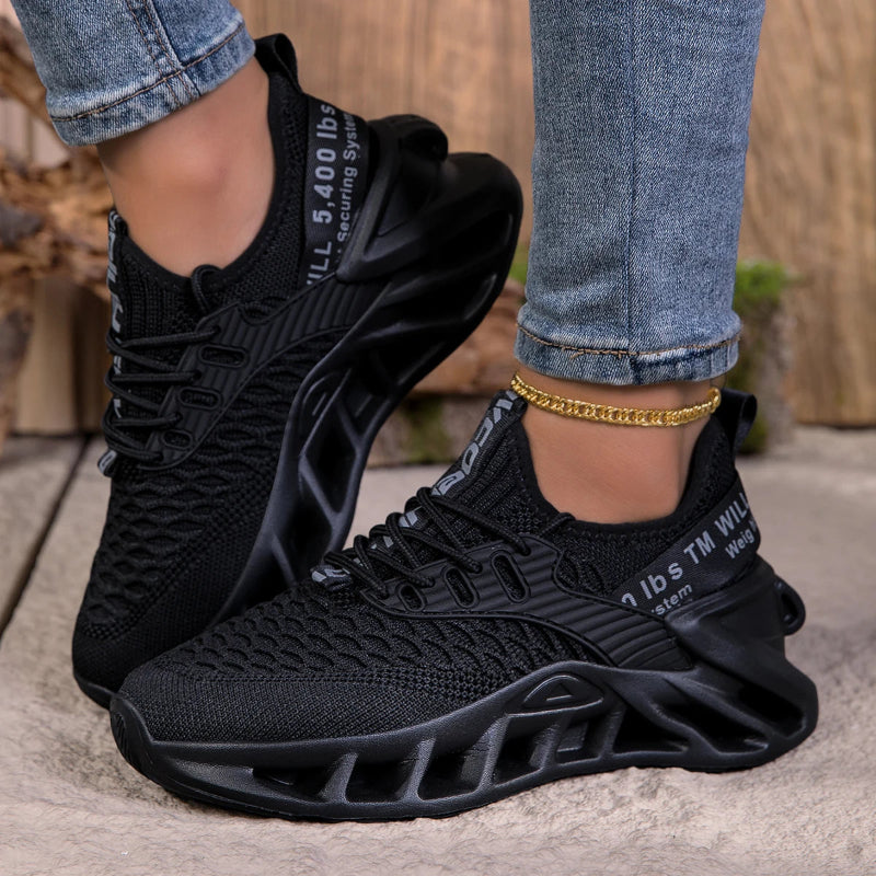 Black sneakers worn with rolled-up jeans on a neutral background