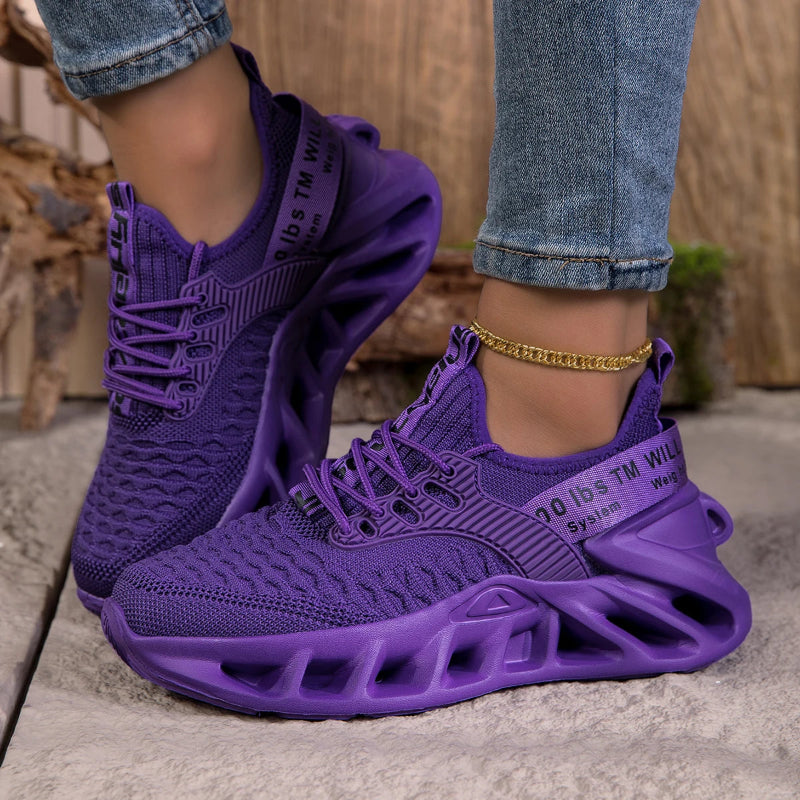 Purple sneakers worn with rolled-up jeans on a neutral background