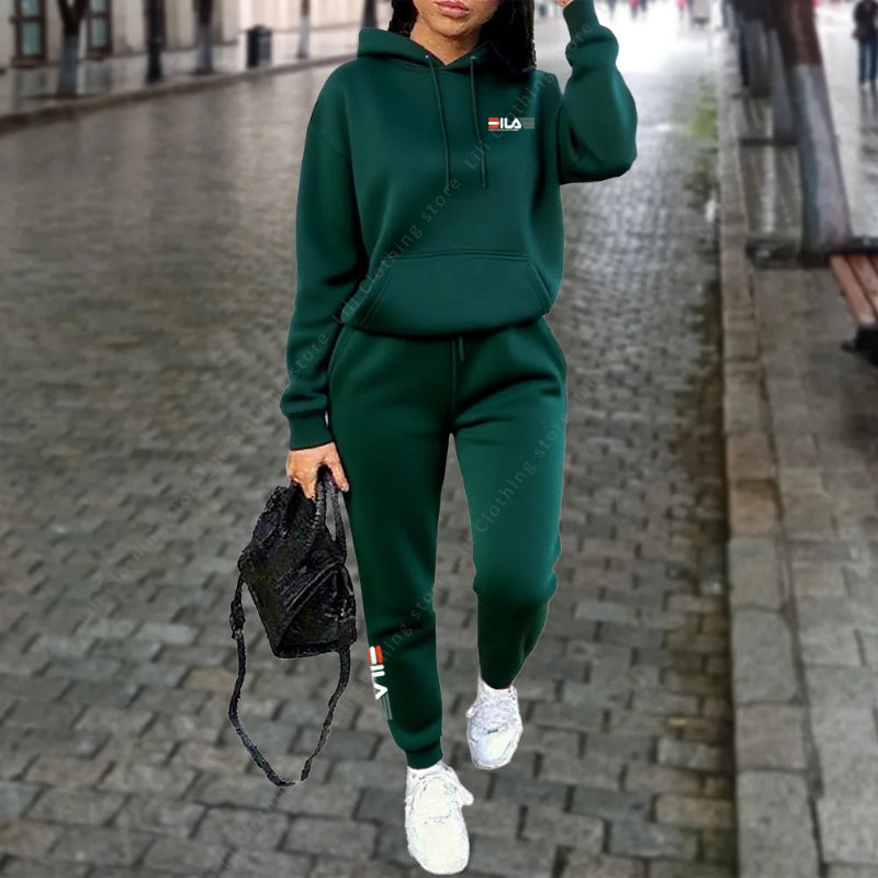 Person wearing a green tracksuit with a brand logo on a paved street.