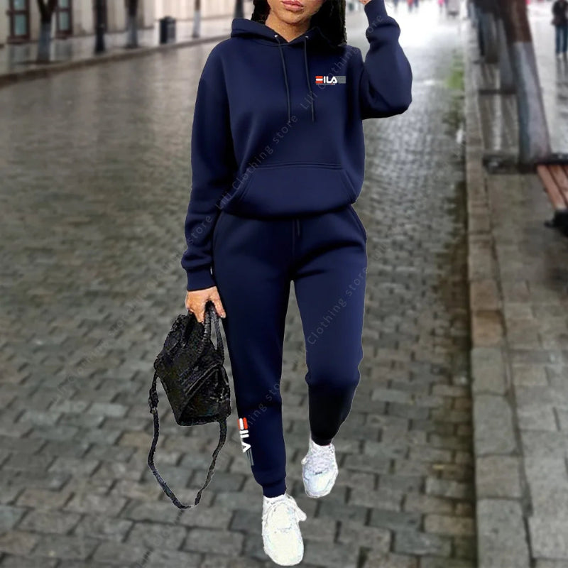 Person wearing a navy blue tracksuit with a logo on a blurred street background