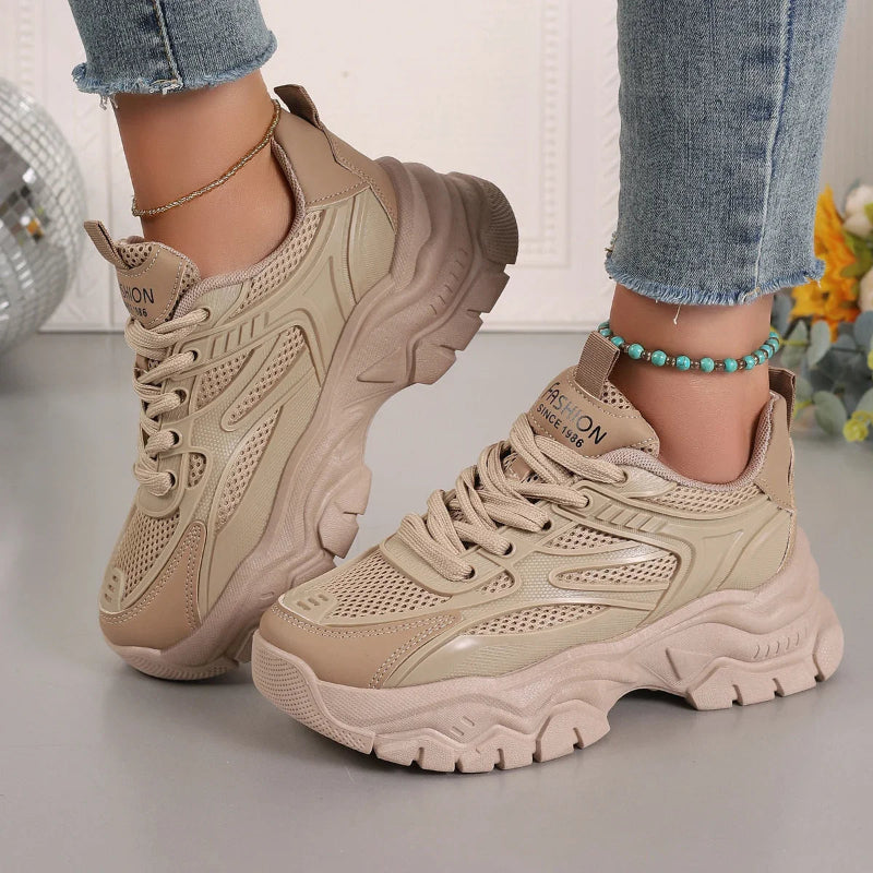 Beige sneakers worn with light blue jeans on a neutral background