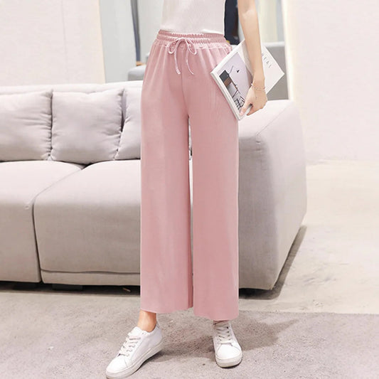 Person wearing pink wide-leg pants and white sneakers in a living room setting.