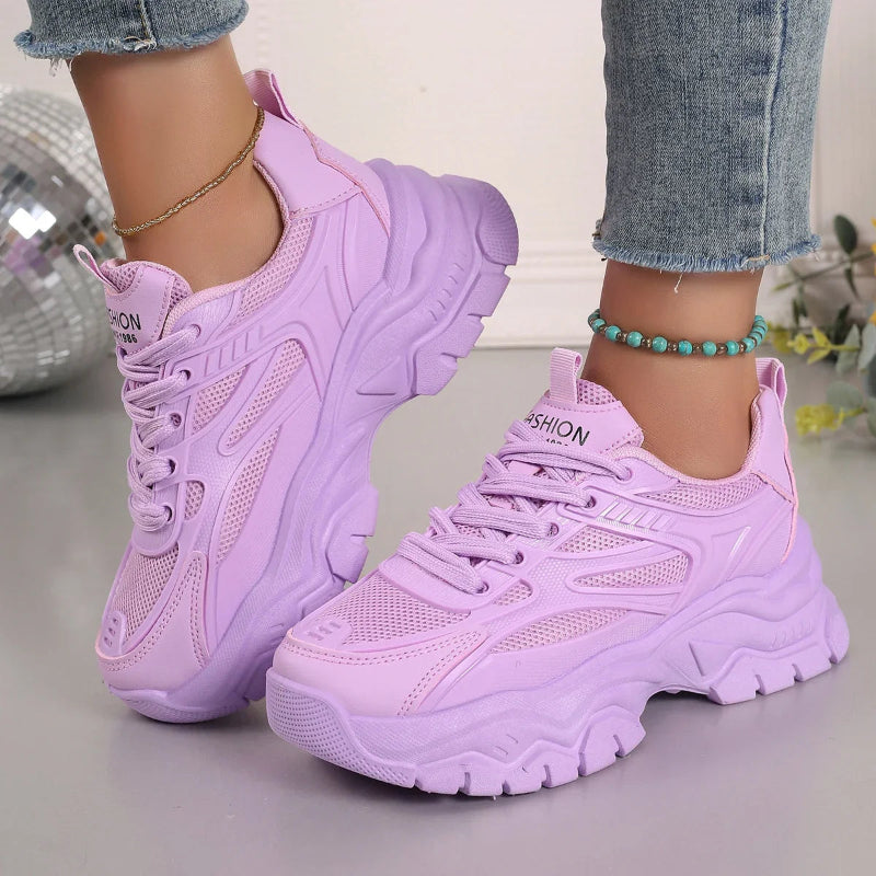 Purple sneakers worn with light blue jeans on a neutral background