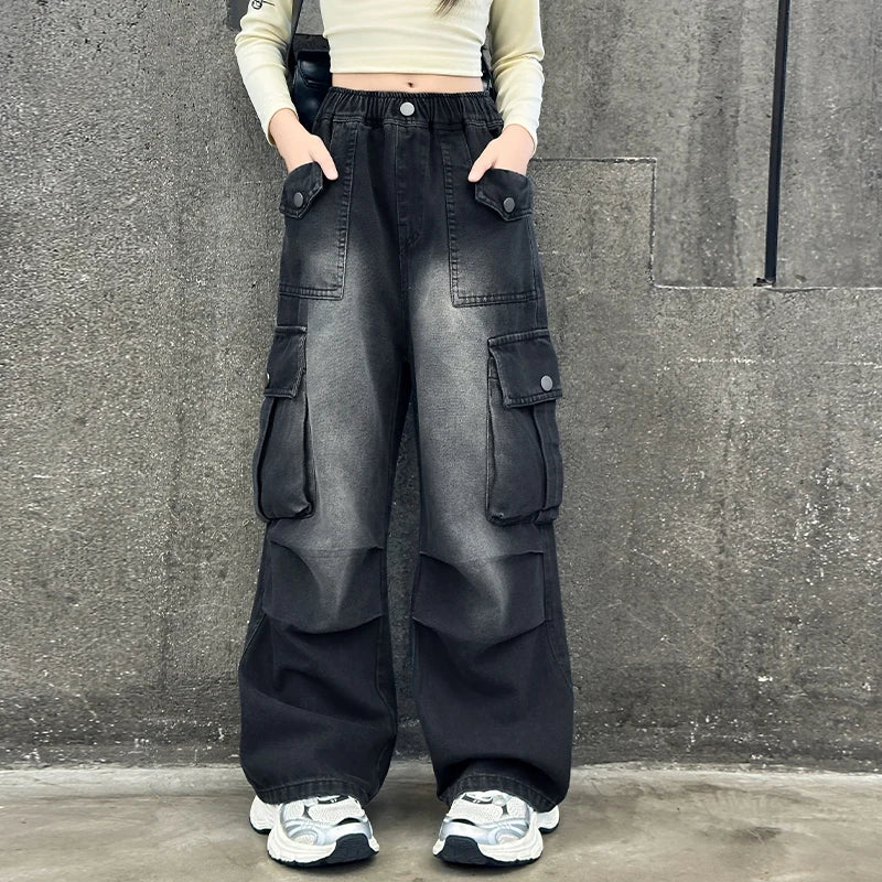 Person wearing black cargo pants standing against a gray wall.