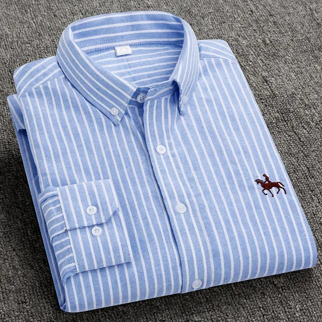 Folded blue and white striped shirt with a logo on a gray surface