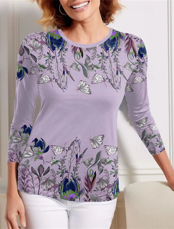 Woman wearing a purple floral and butterfly patterned top indoors.