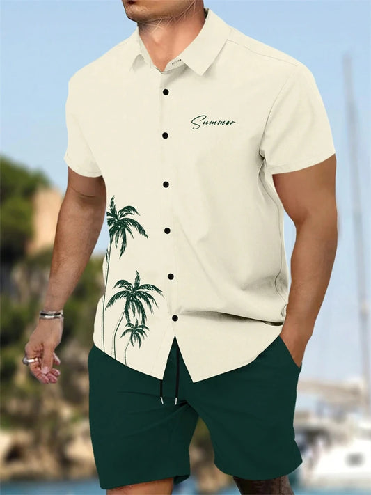 Man wearing a beige shirt with palm tree design and green shorts, standing by a waterfront.