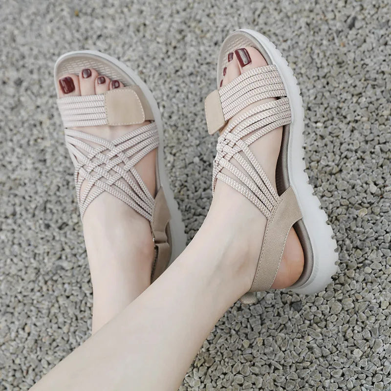 Beige sandals worn on a textured gray surface
