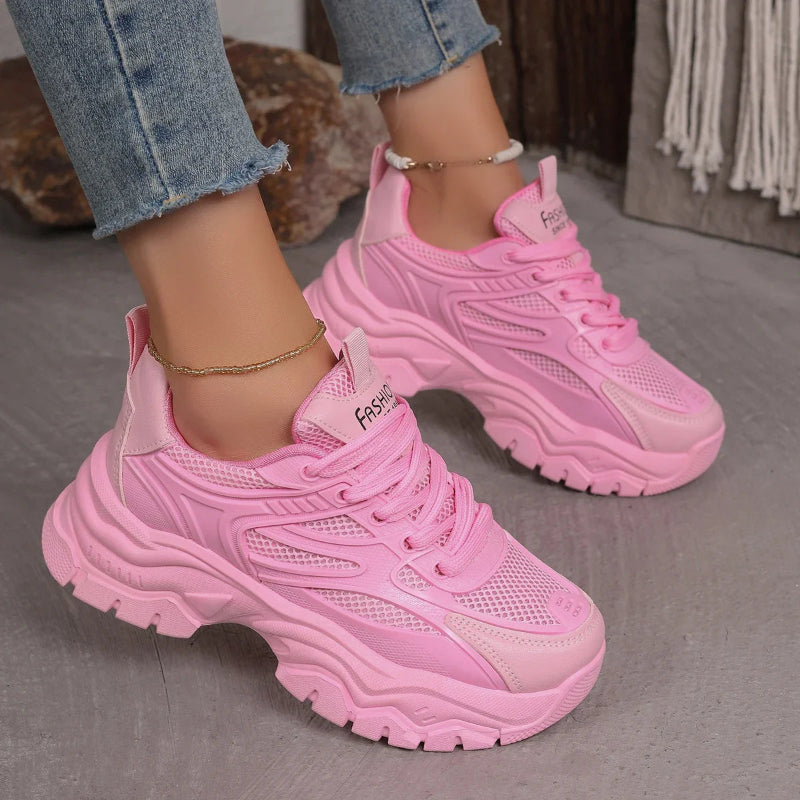 Pink sneakers worn with jeans on a neutral background
