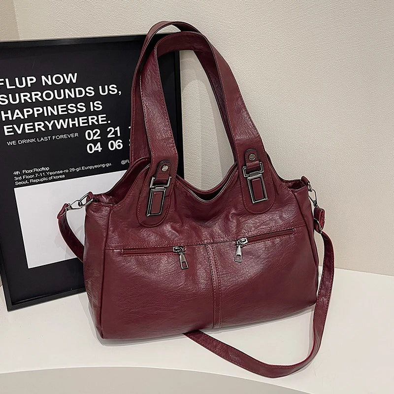 Maroon handbag on a white surface with a black frame in the background