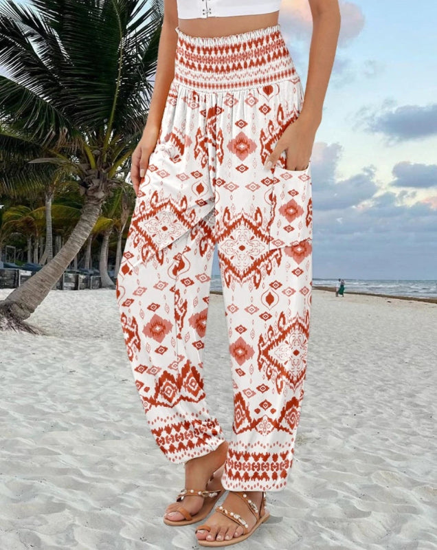Person wearing red and white patterned pants on a beach with palm trees and ocean in the background.