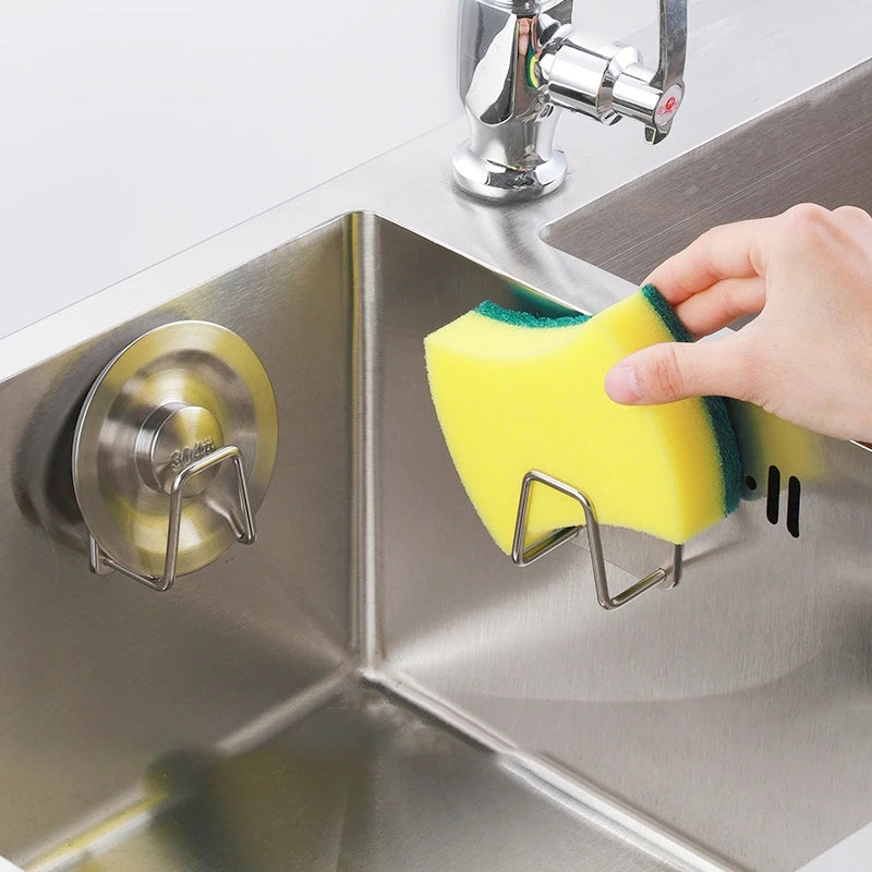 Stainless steel sponge holder mounted inside a kitchen sink holding sponge and brush with water draining 1