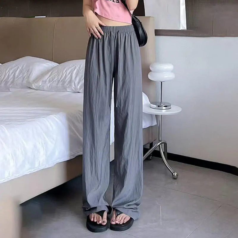 Person wearing gray wide-leg pants in a bedroom setting