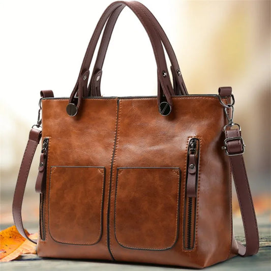 Brown leather handbag with a shoulder strap on a blurred background