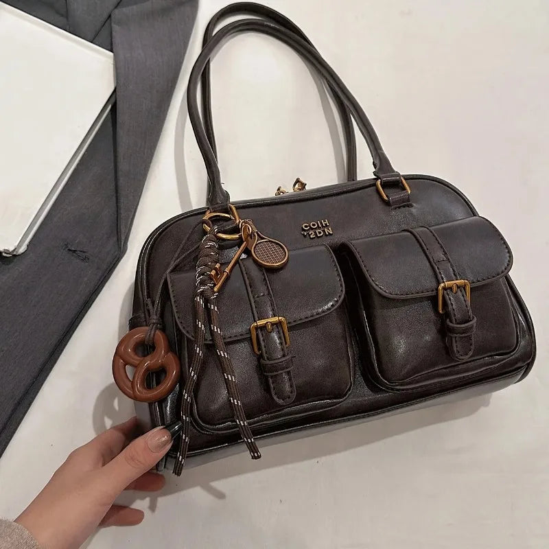 Dark brown leather handbag with gold accents on a light background